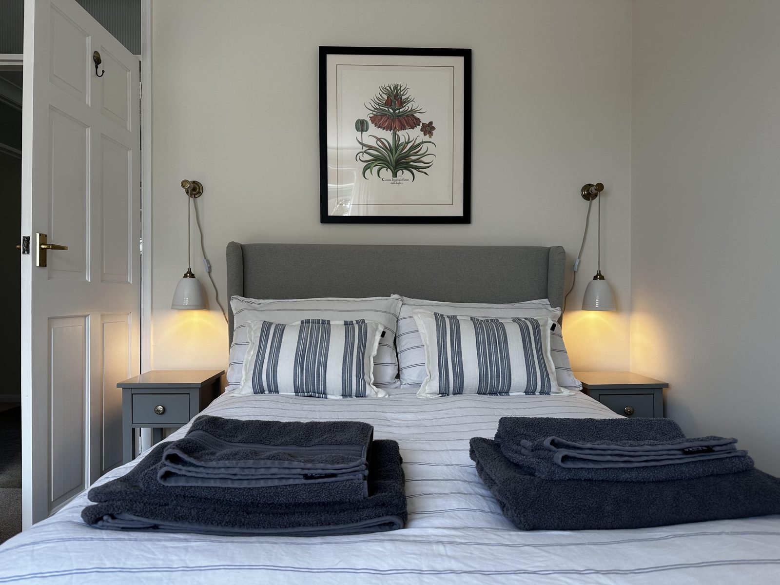 Refurbished courtyard letting room — bed with striped linen and bedside lamps