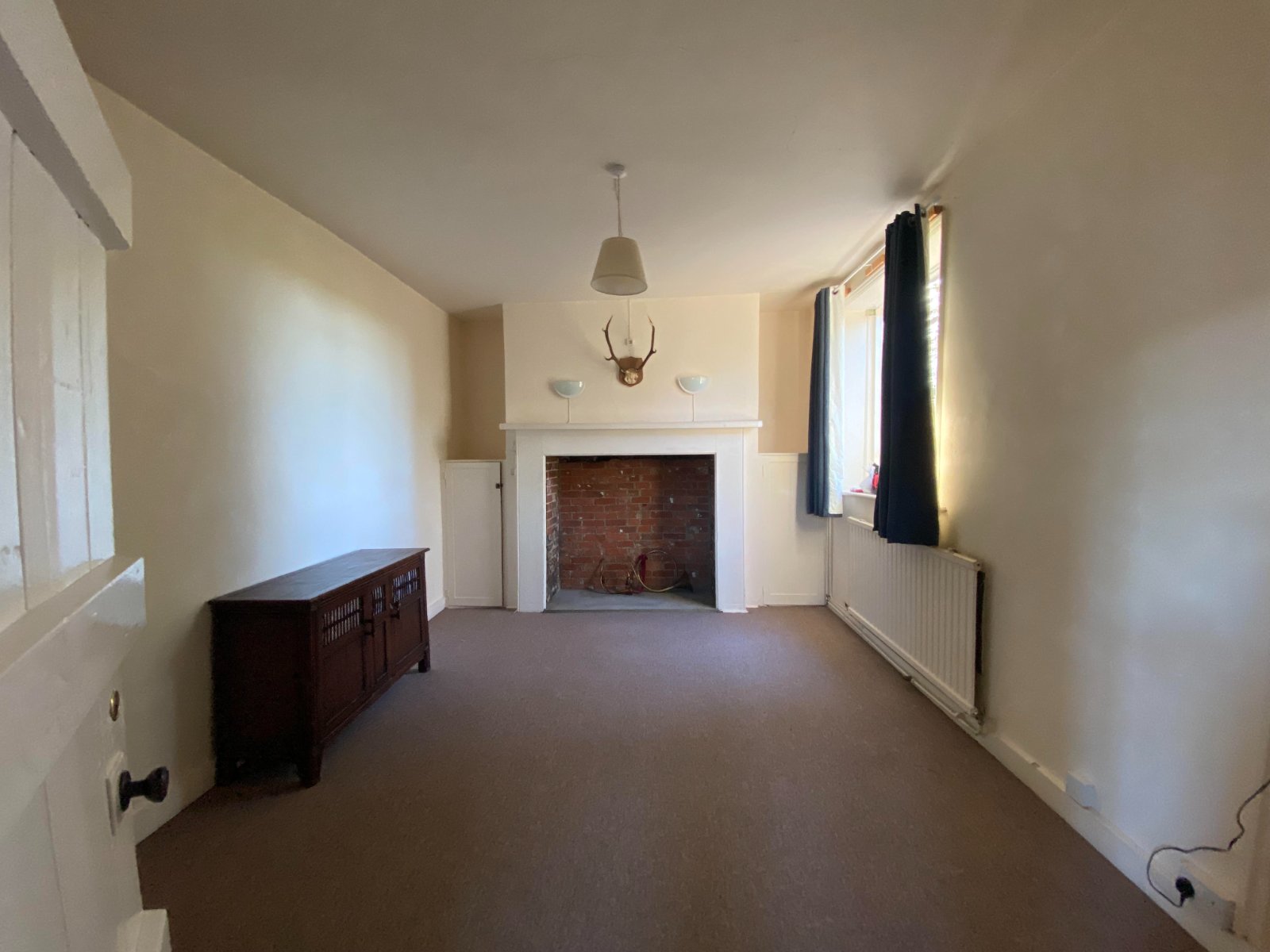Empty reception room with bare fireplace before refurbishment